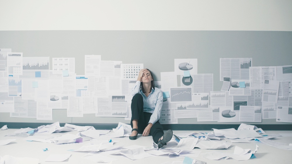exhausted,confused,businesswoman,sitting,on,the,floor,surrounded,by,crumpled